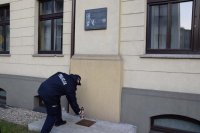 Na fotografii widać pamiątkową tablicę wmurowaną w ścianę budynku Komendy Powiatowej Policji w Atarnowskich Górach. Pod tablicą Komendant Powiatowy Policji w Tarnowskich Górach insp. Krzysztof Hajda stawia zapalonego znicza.