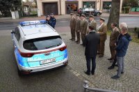 Na fotografii widać policyjny radiowóz, z boku którego stoją: Pierwszy Zastępca Komendanta Powiatowego Policji w Tarnowskich Górach podinsp. Sławomir Bylicki, Komendant Komisariatu Policji w Tworogu, Wójtowie Gmin w Tworogu i Krupskim Młynie oraz przedstawiciele Nadleśnictw.