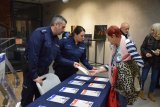 Na fotografii widać od lewej aspiranta sztabowego Adama Cichowskiego i sierżant sztabową Ewelinę Śliwę, którzy stoją przy stoliku z ulotkami. Policjanci przekazują seniorce ulotki informacyjne.