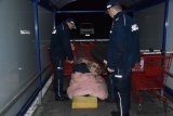 Na fotografii widać wiatę przeznaczoną do przechowywania koszyków sklepowych, pod którą dwóch policjantów oraz pracownik socjalny stoją przed legowiskiem osoby bezdomnej.
