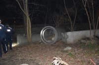 Na fotografii widać leżące na ziemi betonowe rury. Z lewej strony fotografii widać dwóch policjantów
