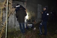 Na fotografii widać dwóch policjantów oraz pracownika noclegowni. Mundurowy wchodzi do budynku przez wyrwę w murze