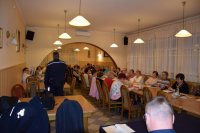 Na fotografii widać siedzące przy stołach osoby. Na zdjęciu widać również policjanta, który jest odwrócony tyłem