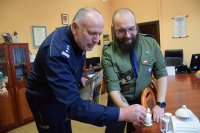 Na fotografii widać od lewej Komendanta Powiatowego Policji w Tarnowskich Górach insp. Krzysztofa Hajdę oraz harcerza, który przekazuje komendantowi Betlejemskie Światło Pokoju