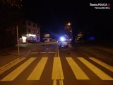 Na fotografii widać przejście dla pieszych, za którym widać samochód osobowy. W tle fotografii widać policyjny radiowóz blokujący drogę.