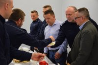 Na fotografii widać Komendanta Powiatowego Policji w Tarnowskich Górach insp. Krzysztofa Hajdę, który przekazuje opłatek zgromadzonym osobom.