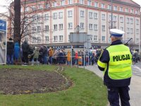 Na fotografii widać odwróconego tyłem policjanta, który obserwuje tłum ludzi.