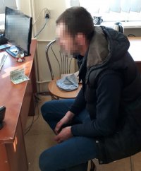 Na fotografii widać siedzącego przy biurku mężczyznę. Na biurku widać m.in. zabezpieczoną przez policjantów gotówkę