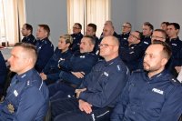 grupa siedzących na krzesłach policjantów