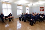 przy stoliku siedzi od prawej Pierwszy Zastępca Komendanta Wojewódzkiego Policji w Katowicach insp. Roman Rabsztyn oraz  Komendant Powiatowy Policji w Tarnowskich Górach insp. Krzysztof Hajda. Z prawej strony zdjęcia widać siedzących na krzesłach policjantów oraz zaproszonych gości.