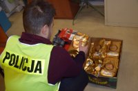 policjant kuca przy kartonach wypełnionych kilogramowymi kawami