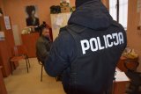 policjant obserwuje siedzącego na krześle zatrzymanego mężczyznę
