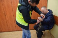 policjant odpina zatrzymanemu kajdanki