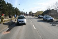 po obydwu stronach drogi zaparkowane samochody osobowe oraz policyjny radiowóz. W tle fotografii widać zaparkowany na drodze wóz strażacki oraz ciężarówka.