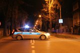 Na fotografii widać drogę, w poprzek której stoi zaparkowany policyjny radiowóz