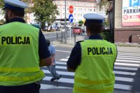 Na fotografii widać dwóch odwróconych tyłem policjantów, którzy obserwują przejście dla pieszych