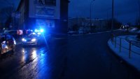 na drodze radiowóz policyjny z włączonymi sygnałami świetlnymi stoi zaparkowany obok uszkodzonego samochodu osobowego. W oddali, na drodze  widać zaparkowany autobus