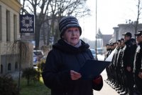 Przedstawicielka Zarządu Stowarzyszenia Rodziny Katyńskiej przy Komendzie Policji odczytuje list. Z prawej strony zdjęcia widać grupę młodzieży z klas policyjnych. W tle fotografii widać policyjną gwiazdę.