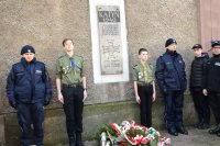 Przy murze kościoła, obok tablicy katyńskiej, stoją - pełnią warte policjanci i harcerze.