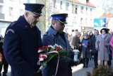 fotografia kolorowa.  Pierwszy Zastępca Komendanta Powiatowego Policji w Tarnowskich Górach podinsp. Sławomir Bylicki wraz z Dyrektorem Aresztu stoją  z wiązanką kwiatów i zapalonym zniczem