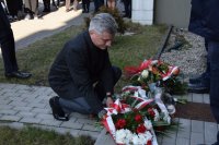 Wicestarosta tarnogórski Sebastian Nowak składa kwiaty przed tablicą wmurowaną w ścianę Komendy Powiatowej.