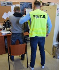 Na fotografii widać jak policjant trzyma za rękę osobę zatrzymaną