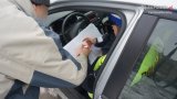 na fotografii widać mężczyznę, który stoi przy policyjnym radiowozie i podpisuje mandat karny