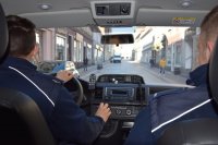 fotografia kolorowa: wnętrze radiowozu. Na przednich fotelach siedzą policjanci