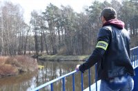 fotografia kolorowa: policjant stoi na kładce i obserwuje zalew