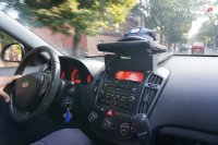 fotografia kolorowa: na fotografii widać wnętrze policyjnego radiowozu. Przez przednią szybę widać  ulicę i jadące nią samochody osobowe