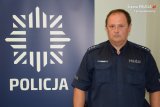 fotografia kolorowa: dzielnicowy asp. szt. Piotr Gawęda. Z lewej strony zdjęcia widać policyjną gwiazdę, pod którą znajduje się napis POLICJA