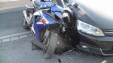 fotografia kolorowa: motocykl oparty o prawy bok samochodu osobowego. Przód motocykla jest uszkodzony