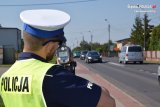 Na fotografii widać policjanta, który ma przystawione do twarzy urządzenie służące do pomiaru prędkości.