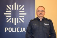 na zdjęciu dzielnicowy Brzezina przy banerze z napisem policja