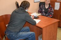 fotografia kolorowa: po obydwu stronach biurka siedzą dwaj mężczyźni. Jeden z nich to policjant, który przesłuchuje sprawcę.
