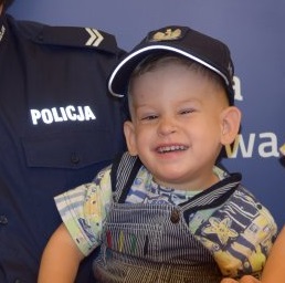 Na fotografii widać Jasia Jabłońskiego, który na głowie ma policyjną czapkę.