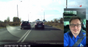 Na zdjęciu widać drogę widzianą okiem kamery samochodowej, po której jadą samochody. Z prawej strony zdjęcia widać mężczyznę zapiętego pasami bezpieczeństwa
