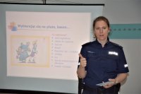 fotografia kolorowa: policjanta obok niej ekran z wyświetloną grafiką dotyczącą bezpiecznych postaw