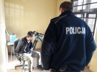 na fotografii widać policjanta, który patrzy na siedzącego na krześle, zatrzymanego mężczyznę