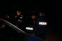 Na fotografii widać dwóch policjantów interweniujących wobec mężczyzny. Interwencja przebiega w nocy.