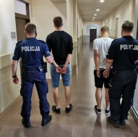 dwóch sprawców rozboju na korytarzu w prokuraturze trzymani przez policjantów