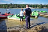 policjant stojący na brzegu jeziora nakło chechło, w tle rowerek i stojąca kobieta