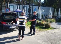 policjant stojący obok radiowozu nieoznakowanego, obok niego sprawca wykroczenia - mężczyzna