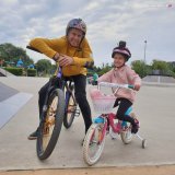 mężczyzna i dziewczynka na rowerze na terenie skate parku