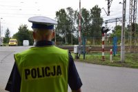 policjant stojący przed przejazdem kolejowym
