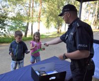 policjant wręczający odblaski dwóm dzieciom