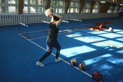 Zdjęcie przedstawia halę sportową, na której dziewczyna rzuca piłką lekarską