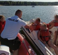zdjęcie przedstawia akwen, na środku którego, policjant sprawdza stan trzeźwości osób znajdujących się na rowerku wodnym