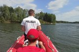 Zdjęcie przedstawia akwen, po którym płynie łódź motorowa. W łodzi znajduje się policjant oraz ratownik WOPR