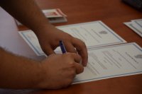 Na zdjęciu widać dłonie składające podpis pod ślubowaniem